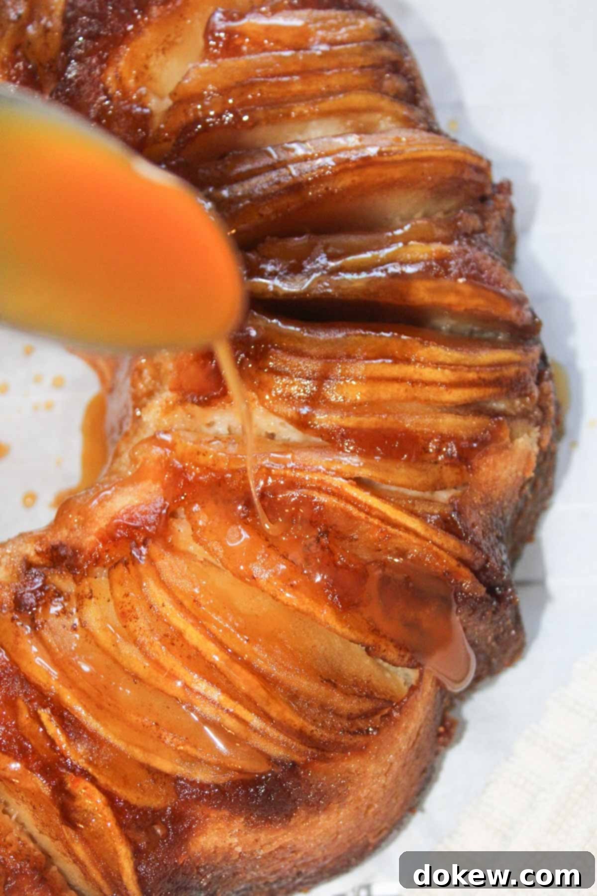 Golden Caramel Apple Bundt 10 Drizzling caramel sauce from a spoon over apple upside down bundt cake.
