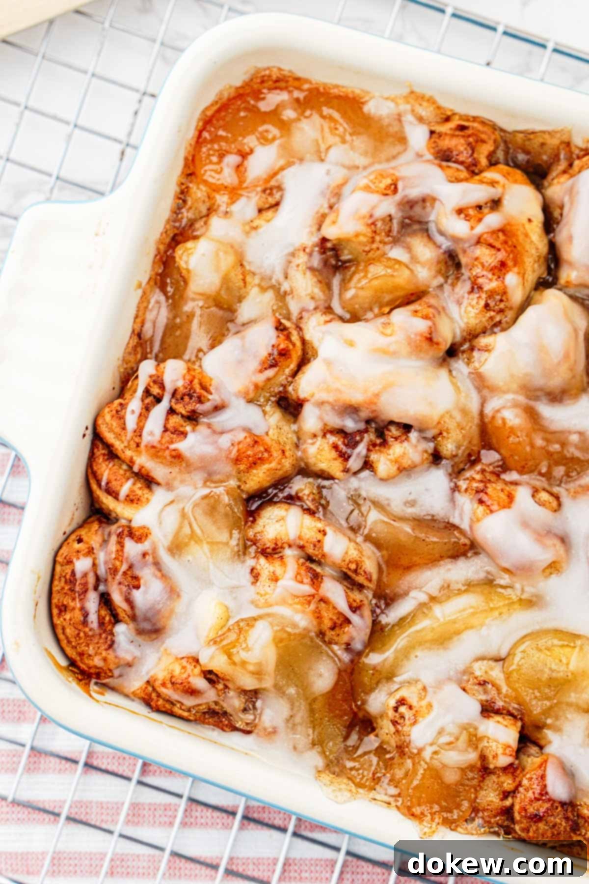Simple Two-Ingredient Apple Cinnamon Delight 6 Close-up of the finished apple cinnamon roll bake, topped with a generous amount of white glaze and ready to be served, highlighting its appealing texture.