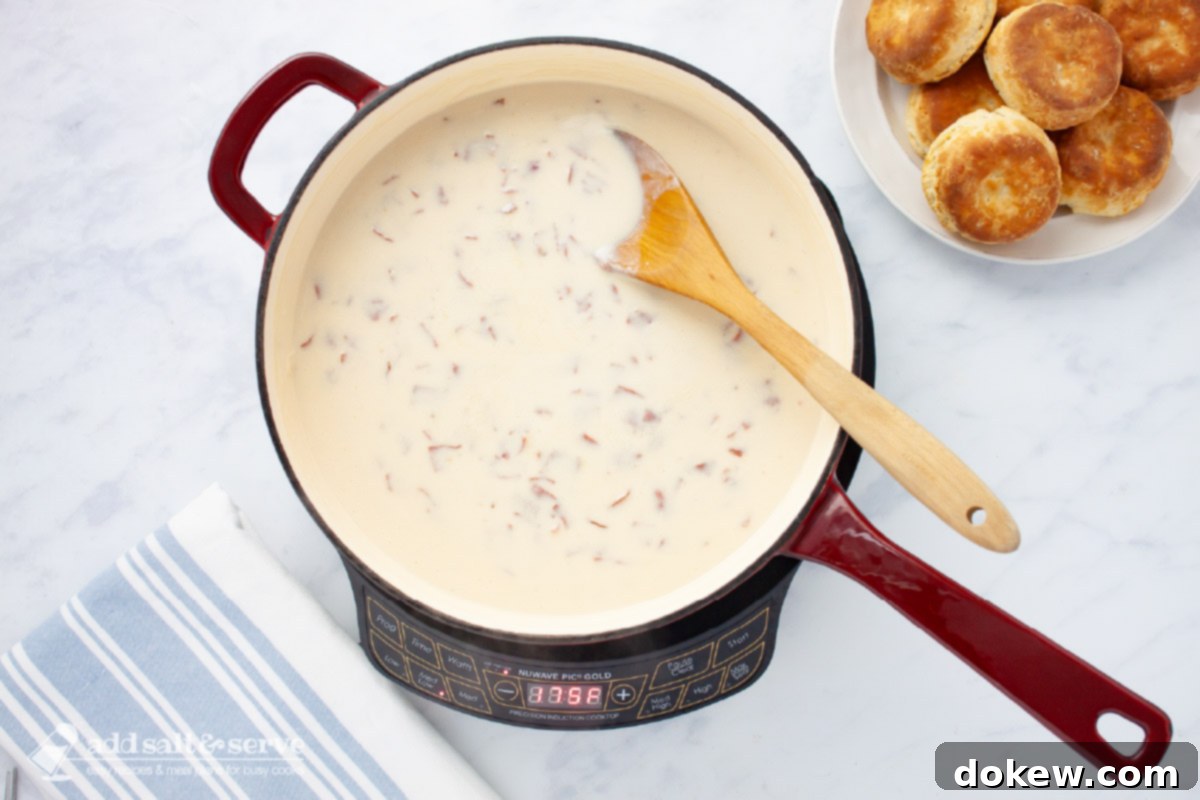Hearty Chipped Beef Gravy 6 Skillet of creamy chipped beef gravy with a wooden spoon beside a plate of biscuits, ready to be served.