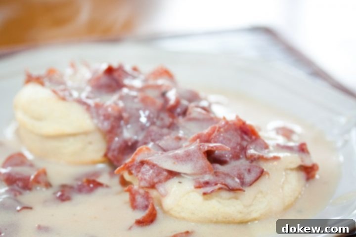 Chipped Beef Gravy Close-up of creamy Chipped Beef Gravy served over biscuits on a white plate, highlighting the rich texture and delicious appeal.