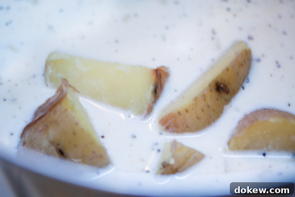 Loaded Baked Potato Soup 4 Chopped potatoes being added to a creamy soup base in a saucepan.