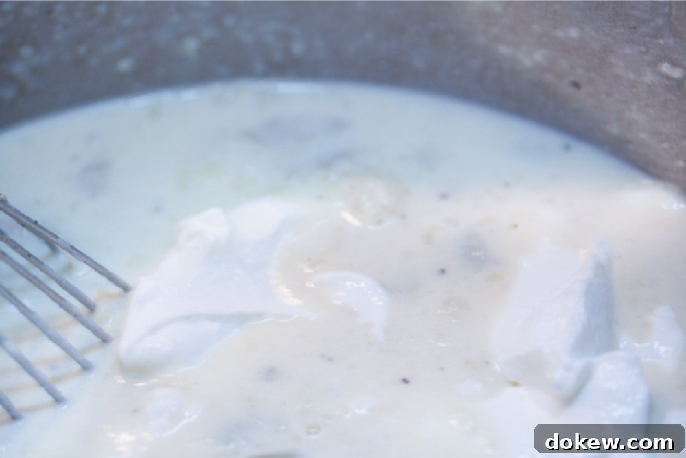 Loaded Baked Potato Soup 7 A whisk mixing sour cream into a bowl of baked potato soup, adding a final touch of richness and tang.