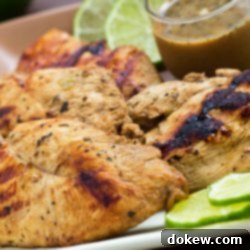 Zesty Basil Lime Chicken 3 Grilled chicken on a square plate, garnished with lime slices. A small clear glass cup of Dijon basil lime dipping sauce is on the plate.