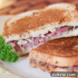 Two Reuben sandwiches on a white plate.