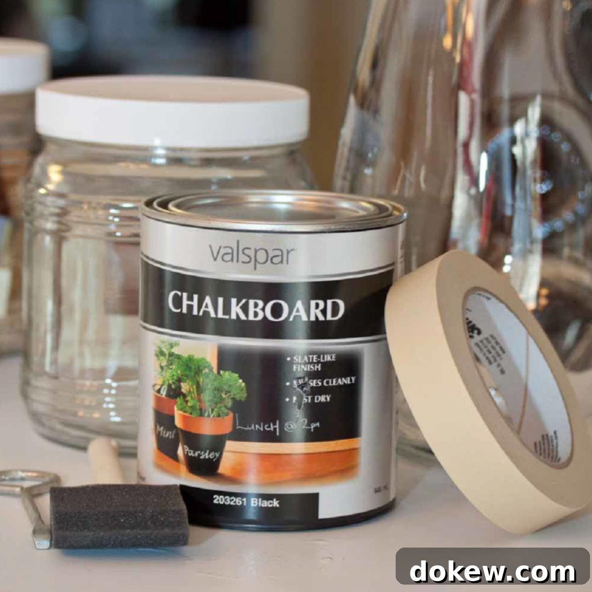 Chalkboard Jar Labels: Quick & Stylish DIY 2 Chalkboard paint, brushes, and various supplies arranged with clear glass jars ready for a DIY project