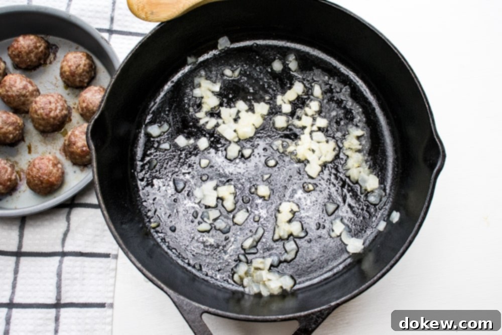 Creamy Balsamic Meatballs Cast iron skillet with chopped onion sautéing and meatballs in a round baking pan to the side