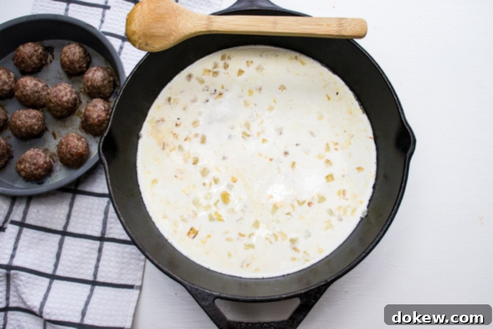 Creamy Balsamic Meatballs Cast iron skillet sautéed chopped onion simmering in cream and meatballs in a round baking pan to the side