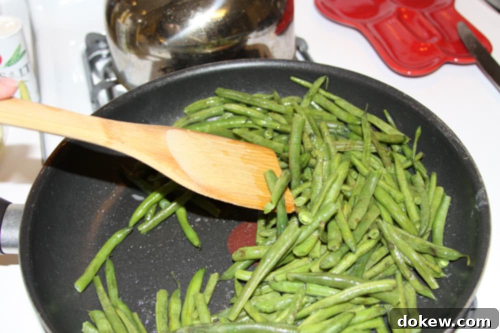Green Beans Seasoned with Italian Dressing green beans being sautéed in a black frypan