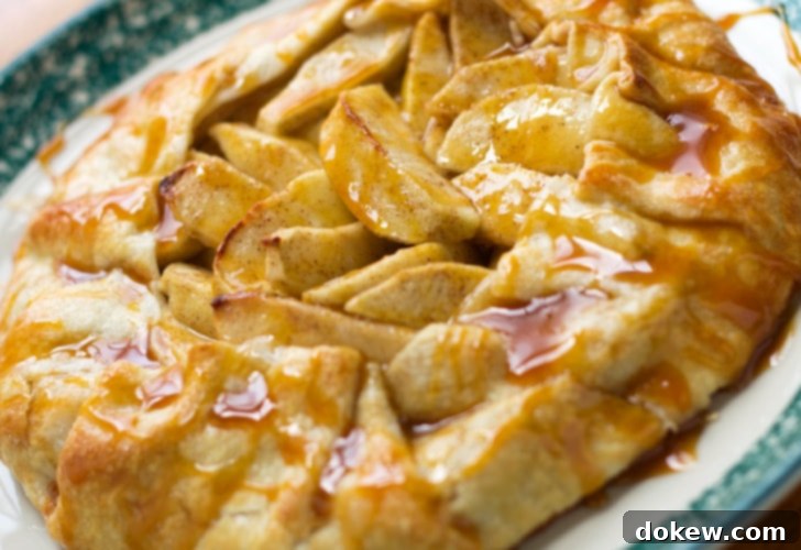 Baked apple galette drizzled with caramel sauce, served on a white plate