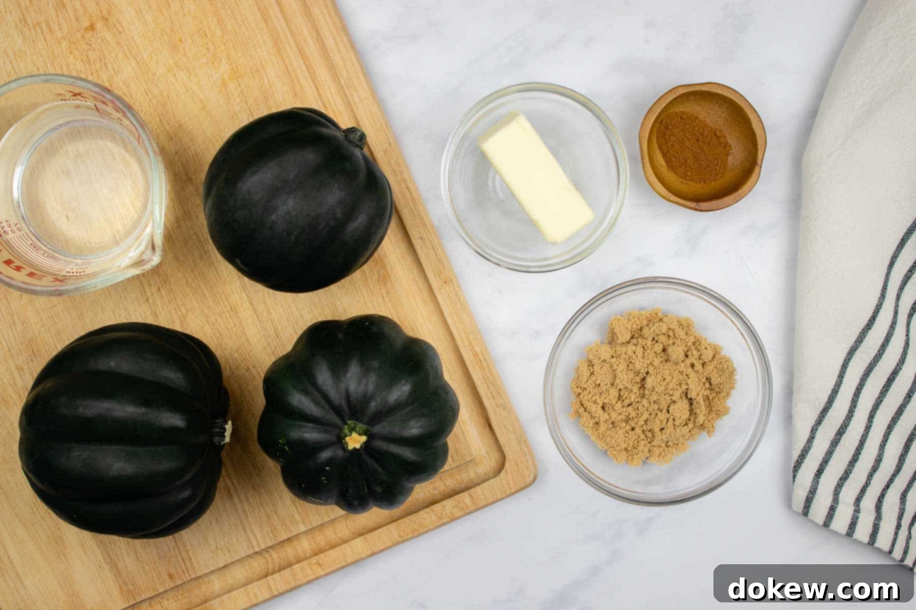 Quick and Easy Microwave Acorn Squash 3 A collection of ingredients neatly arranged for making candied acorn squash, including a whole squash, a stick of butter, a bowl of brown sugar, and a small jar of cinnamon.