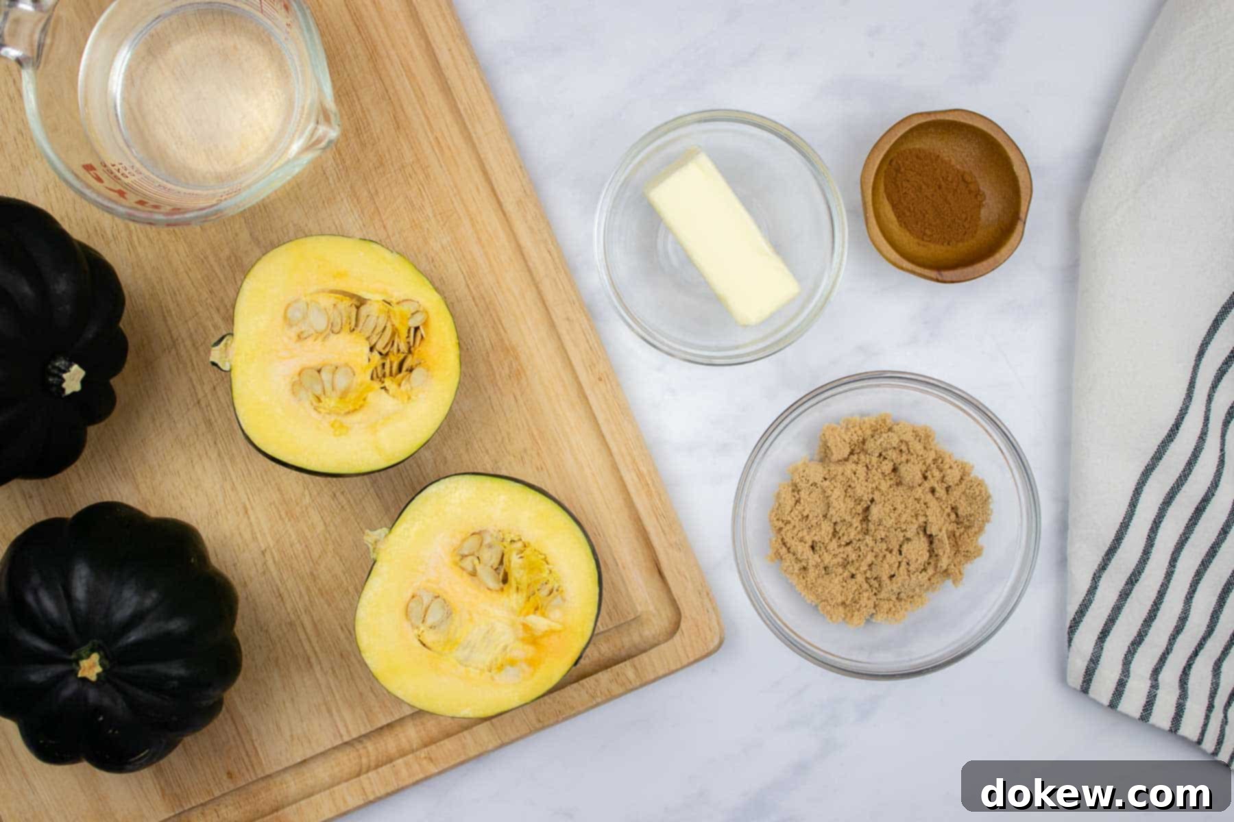 Quick and Easy Microwave Acorn Squash 4 Two halves of acorn squash on a cutting board, with a pat of butter, brown sugar, and cinnamon placed beside them, ready for the next step of the recipe.