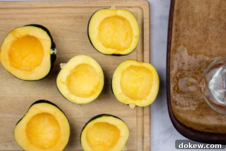 easy-microwave-acorn-squash-ip-4-min Acorn squash cut in half lengthwise and thoroughly cleaned of seeds and pulp, resting on a cutting board, ready for the microwave cooking process.