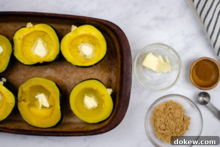 easy-microwave-acorn-squash-ip-3-min Steamed acorn squash halves in a microwave-safe pan, each with a pat of butter melting in its center, ready for the next sweet additions.