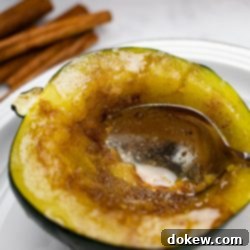 Quick and Easy Microwave Acorn Squash 7 A close-up shot of a single half of candied acorn squash with a spoon scooping out its tender, sweet flesh, ready to be enjoyed.