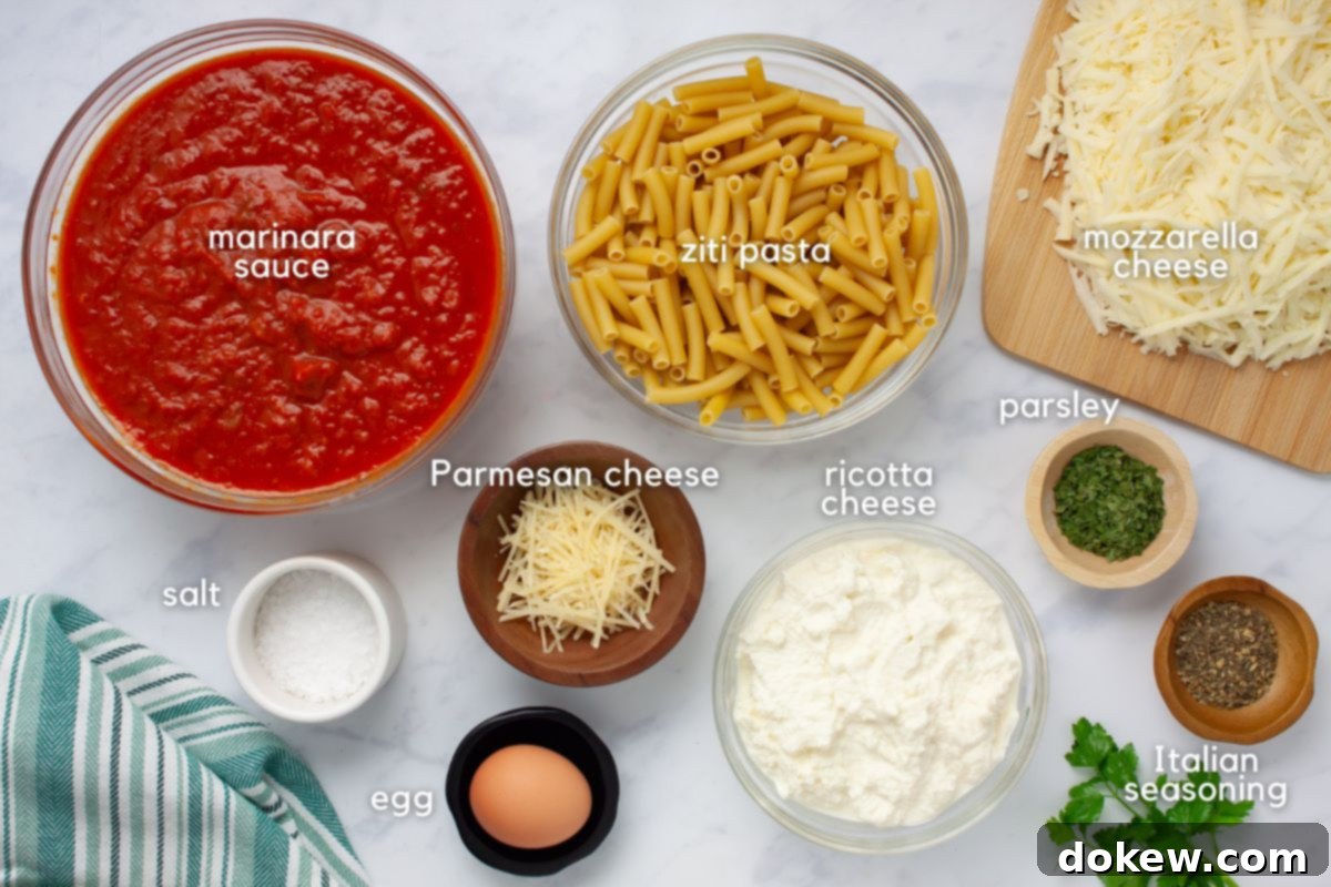 Classic Cheesy Meatless Baked Ziti 3 A vibrant display of ingredients for Cheesy Meatless Baked Ziti, including jars of marinara sauce, uncooked ziti pasta, blocks and shredded mozzarella cheese, a container of Parmesan cheese, a tub of ricotta cheese, fresh parsley, a small dish of Italian seasoning, an egg, and a salt shaker.