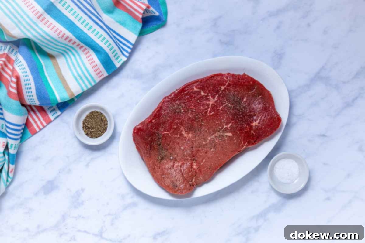 Tender Slow Cooker London Broil in Savory Au Jus 4 Uncooked London broil roast seasoned with salt and pepper.