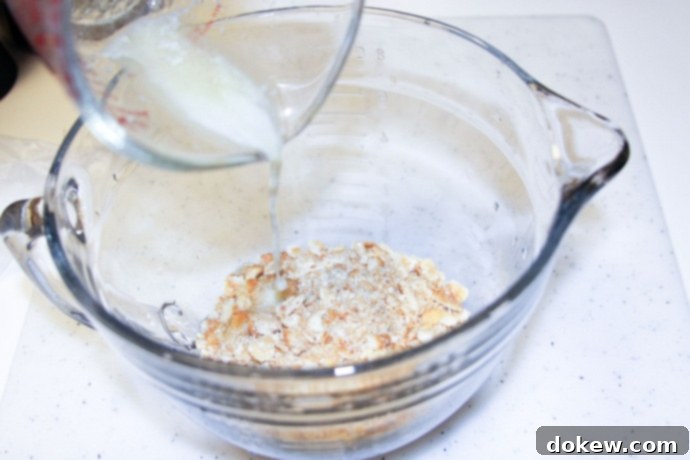 Mixing crushed crackers with melted butter Mixing crushed crackers with melted butter in a bowl, creating the crispy topping for the casserole.
