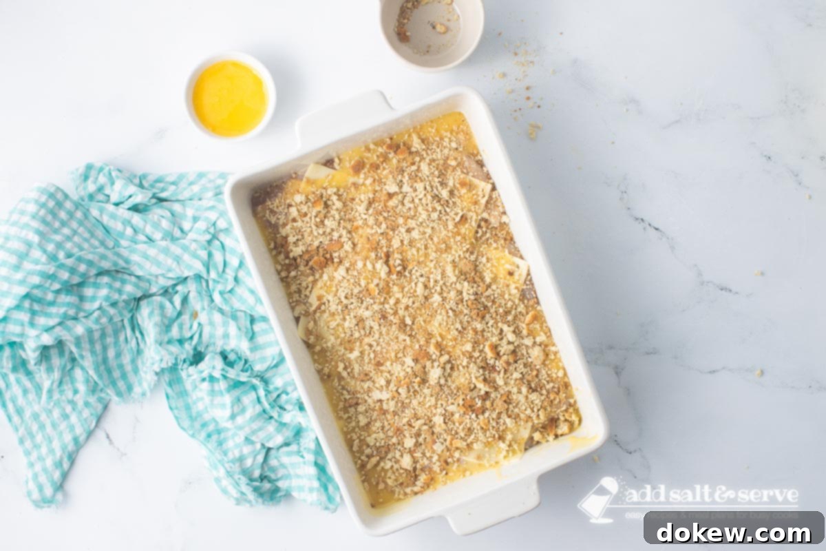 Savory White Wine Swiss Chicken Bake 8 Casserole dish of Swiss chicken with white wine and stuffing before adding melted butter to the top of the stuffing.