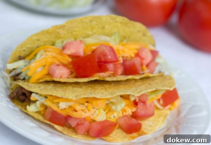 Tacos with shredded lettuce, grated cheese, and chopped tomatoes