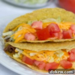 The Taco Spot 2 Tacos with shredded lettuce, grated cheese, and chopped tomatoes