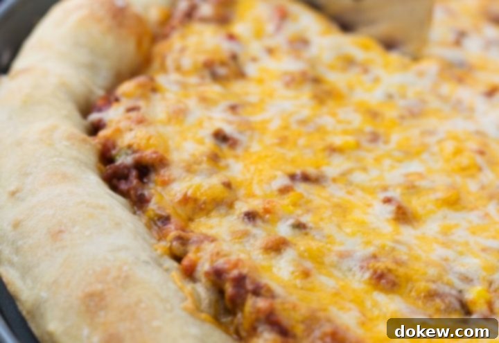 Sloppy Joe Pizza Side view of a whole pizza with sloppy joe sauce covered with colby-jack cheese on a thick crust