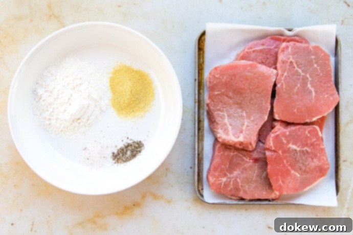 Savory Swiss Steak Flour, dry mustard, salt, and pepper on a white plate. 6 beef steaks on a metal pan.
