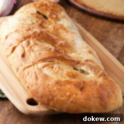 Fresh Garden Stromboli 3 A golden-brown Vegetable Stromboli, sliced open to reveal the vibrant filling, resting on a wooden board.