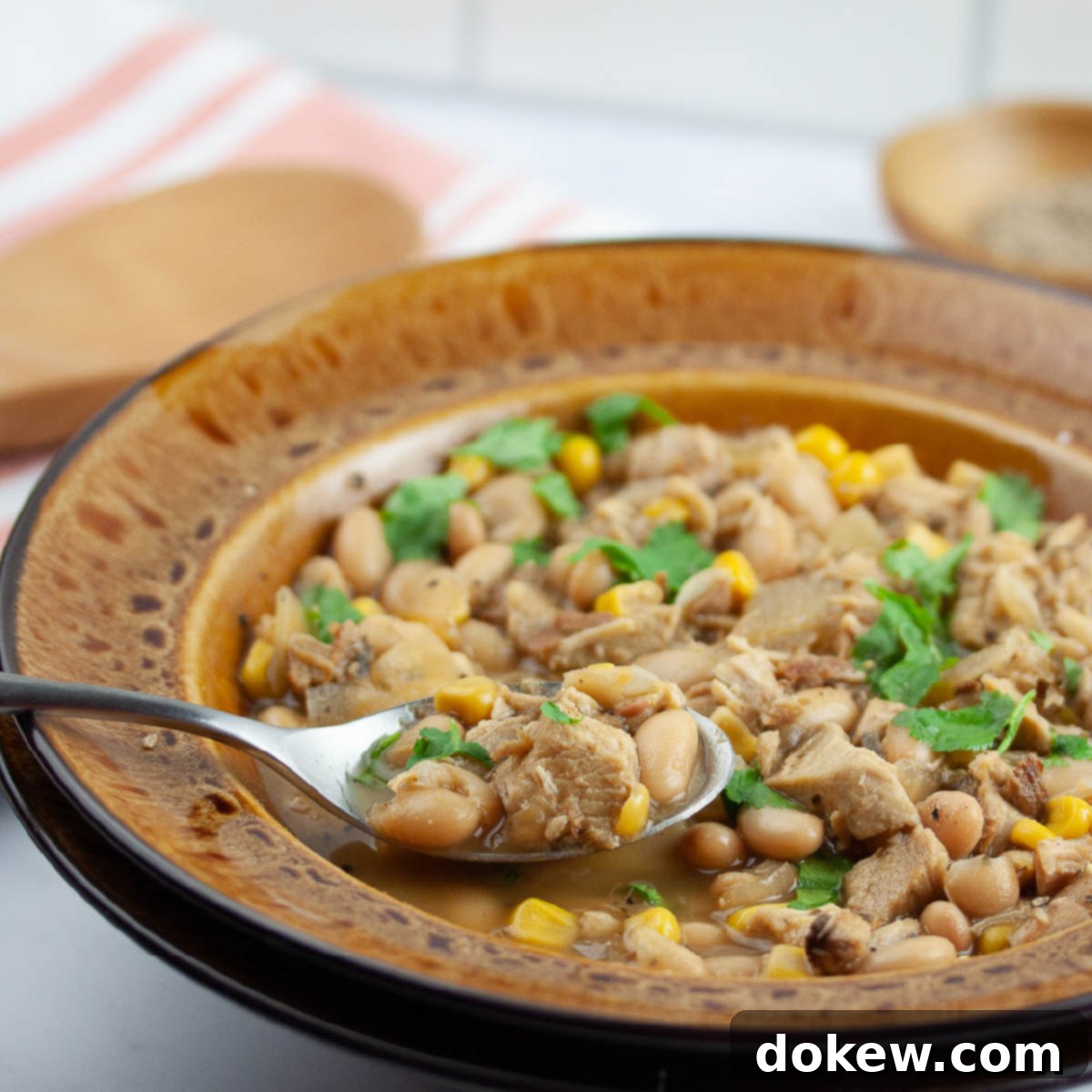 A bowl of Slow Cooker White Chicken Chili garnished with fresh cilantro and avocado slices.