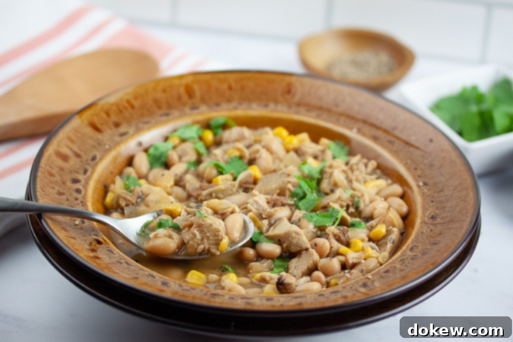 Effortless White Chicken Chili 7 A serving of white chicken chili garnished with fresh cilantro in a rustic bowl.