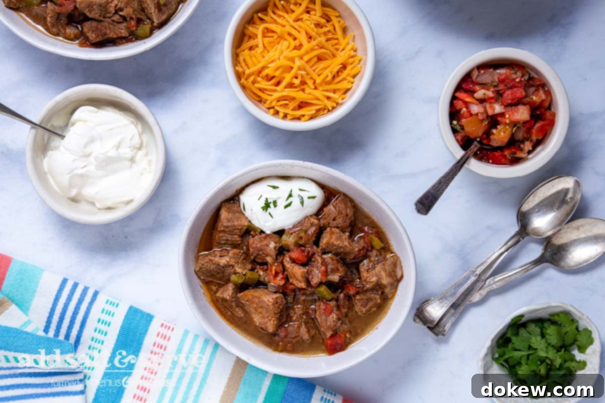Slow Cooker Tender Beef Guisada 8 Overhead view of Carne Guisada made in crock pot with garnishes in small bowls.