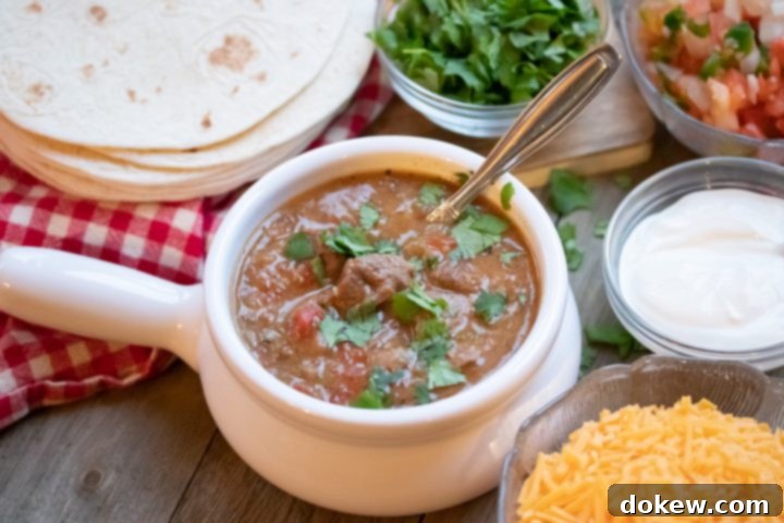 Serving Instant Pot Carne Guisada with Delicious Garnishes A mouth-watering serving of Instant Pot Carne Guisada presented on a clean white surface, accompanied by an array of fresh garnishes: warm tortillas, a bowl of creamy sour cream, vibrant pico de gallo, a pile of shredded cheese, and a fresh sprinkle of cilantro. This image captures the deliciousness and versatility of the Mexican beef stew.