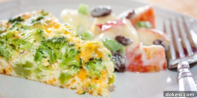 Crustless Broccoli Quiche Slice of broccoli and cheese quiche on a plate with apple and raisin salad on a white plate with a fork.