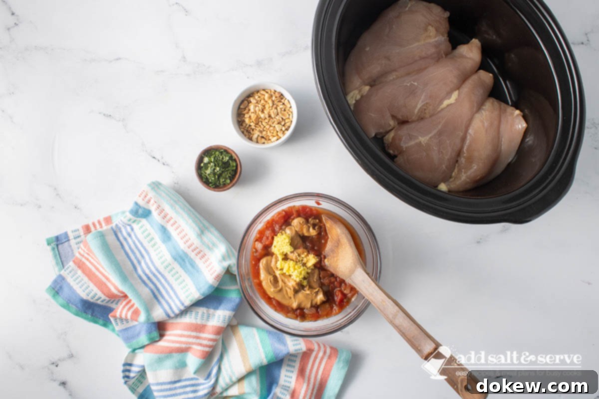 Weeknight Thai Peanut Chicken Magic 5 Uncooked chicken breasts in a slow cooker and small bowls of chopped peanuts and cilantro around a bowl of peanut butter, salsa, soy sauce, grated ginger, and lime juice before mixing.