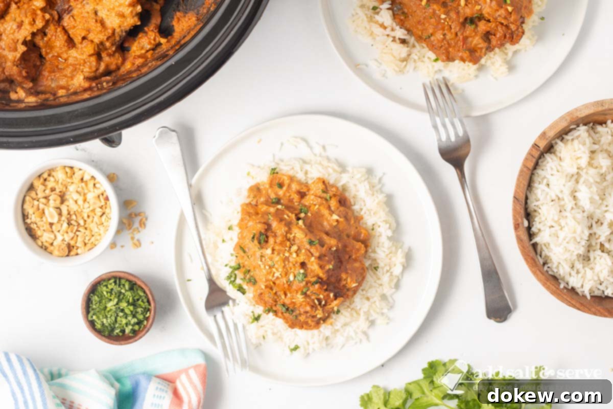 Weeknight Thai Peanut Chicken Magic 8 Plated slow cooker Thai Peanut Chicken over rice garnished with chopped peanuts and cilantro.