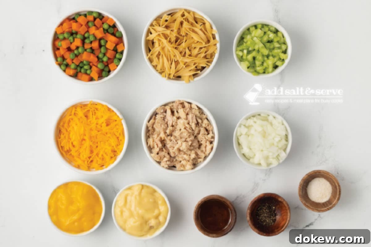 Comforting Tuna Noodle Bake 3 Overhead view of various ingredients including canned tuna, egg noodles, frozen peas and carrots, soups, cheese, onion, and celery, laid out for a cheesy tuna casserole.