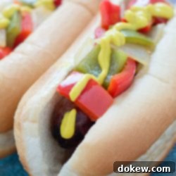 Ultimate Grilled Bratwursts 2 Bratwurst on a hotdog bun with mustard, diced red and green bell peppers and diced onions
