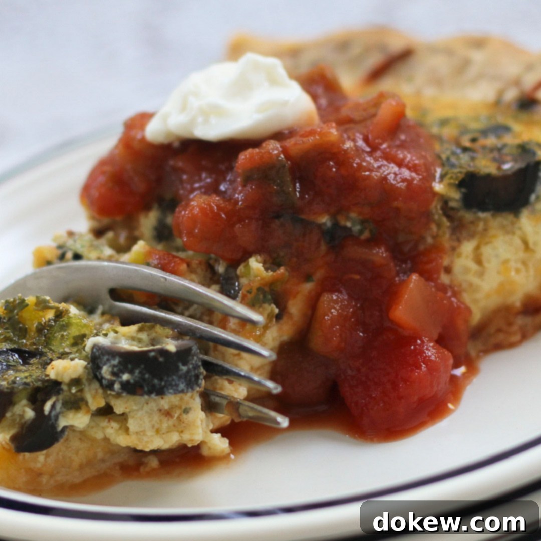 Mexican Fiesta Quiche 2 Photo of a fork cutting into a slice quiche topped with salsa and sour cream