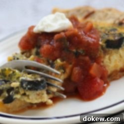 Mexican Fiesta Quiche 3 Photo of a fork cutting into a slice quiche topped with salsa and sour cream