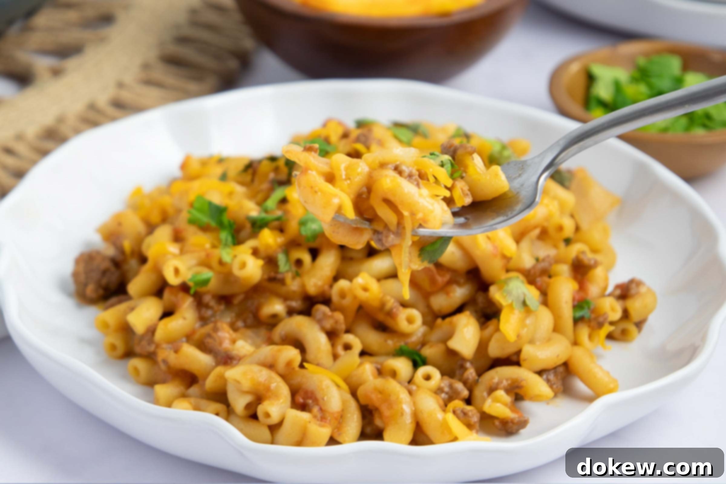 One Pot Taco Macaroni in 30 Minutes 2 Plate of cheesy elbow macaroni and ground beef in seasoned tomatoes garnished with cilantro.