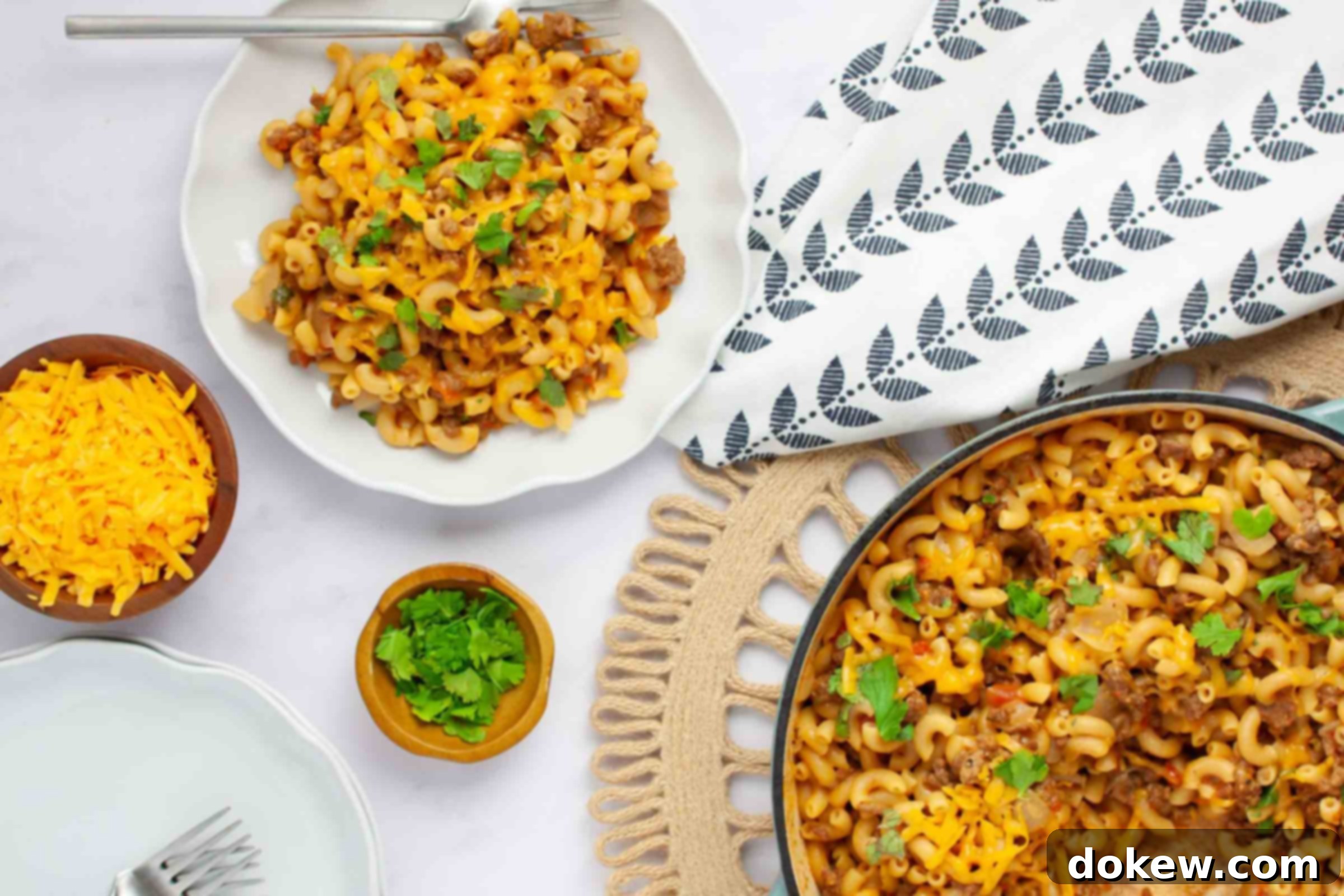 One Pot Taco Macaroni in 30 Minutes 11 Plate of cheesy elbow macaroni and ground beef in seasoned tomatoes garnished with cilantro beside a pan of the same.