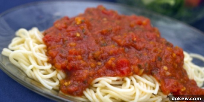 Crockpot Marinara Sauce A pile of cooked spaghetti noodles covered with marinara sauce on a blue plate