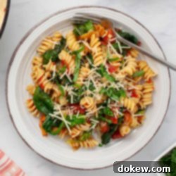 Quick and Easy One-Pot Tomato Spinach Pasta 7 Plate of tomato Spinach Pasta garnished with Parmesan cheese and fresh basil strips.