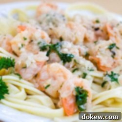 Zesty Garlic Shrimp 2 White plate with shrimp, minced garlic, and parsley on a bed of fettuccine