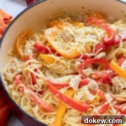 Vibrant Chicken and Bell Pepper Pasta 3 Pasta with chicken, sliced onion, and strips of red and yellow bell peppers cooked in a white sauce in a skillet.