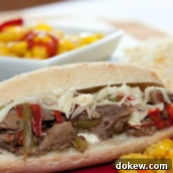 A hoagie roll on a red plate with shredded roast beef, onions, and bell peppers, with a white bowl of pickled peppers in the background.