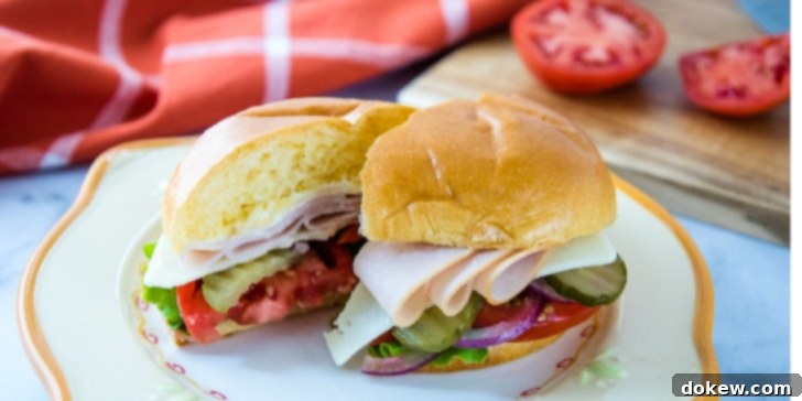 Hearty Turkey & Swiss Hoagies A perfectly assembled turkey and Swiss hoagie on a brioche bun, featuring layers of sliced turkey, Swiss cheese, crisp lettuce, juicy tomato, crunchy pickles, and thinly sliced red onion. The sandwich rests on a vibrant white and orange plate, with a rustic cutting board and fresh tomato in the softly blurred background.