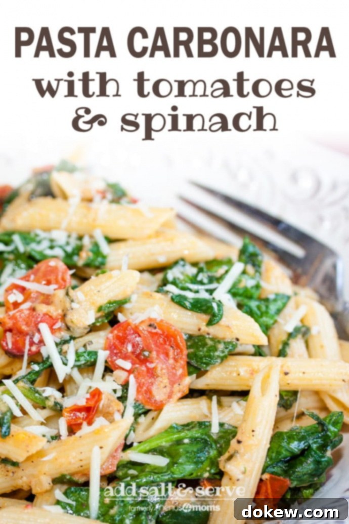 Pasta Carbonara with Tomatoes and Spinach - Pin Image A vibrant close-up of a white plate generously piled with penne pasta, perfectly wilted baby spinach, bright red halved cherry tomatoes, and a dusting of shredded Parmesan cheese. A fork is poised for a bite. The image is overlaid with text that reads 'Pasta Carbonara with Tomatoes & Spinach – Add Salt & Serve (formerly Menus4Moms)', making it ideal for sharing on Pinterest.